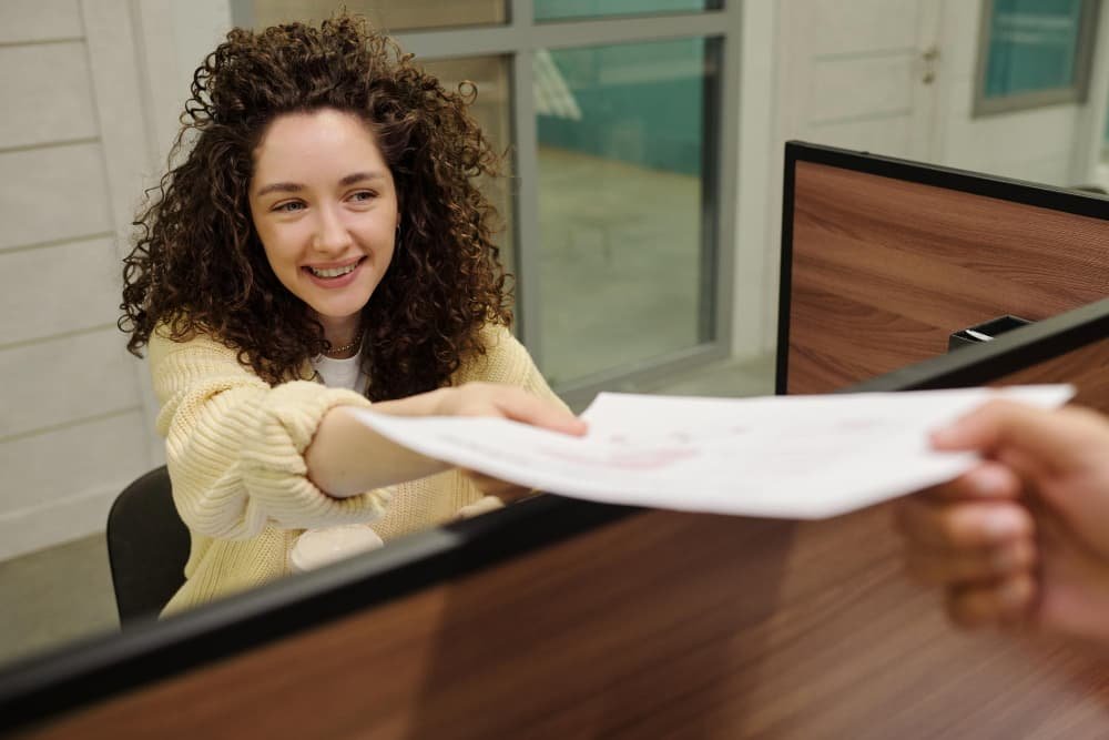 Jeune réceptionniste souriante transmettant un document