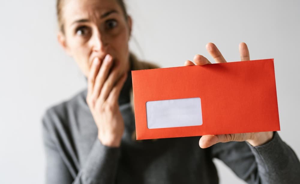 Femme choquée tenant une enveloppe