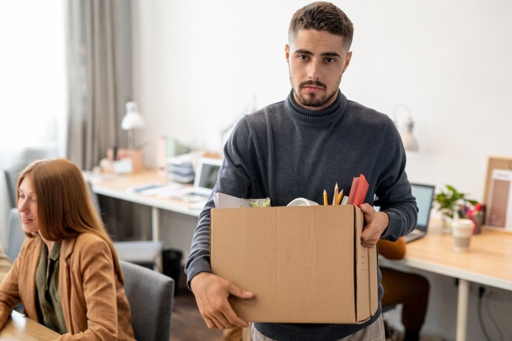 Jeune employé malheureux tenant une boîte avec des fournitures de bureau